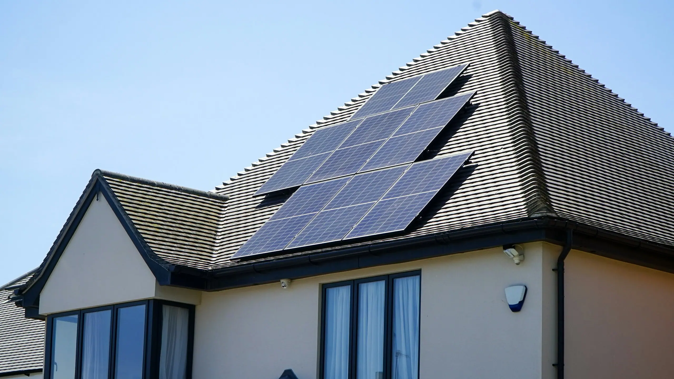 Solar panels on the slate roof of a UK family home under a clear sky